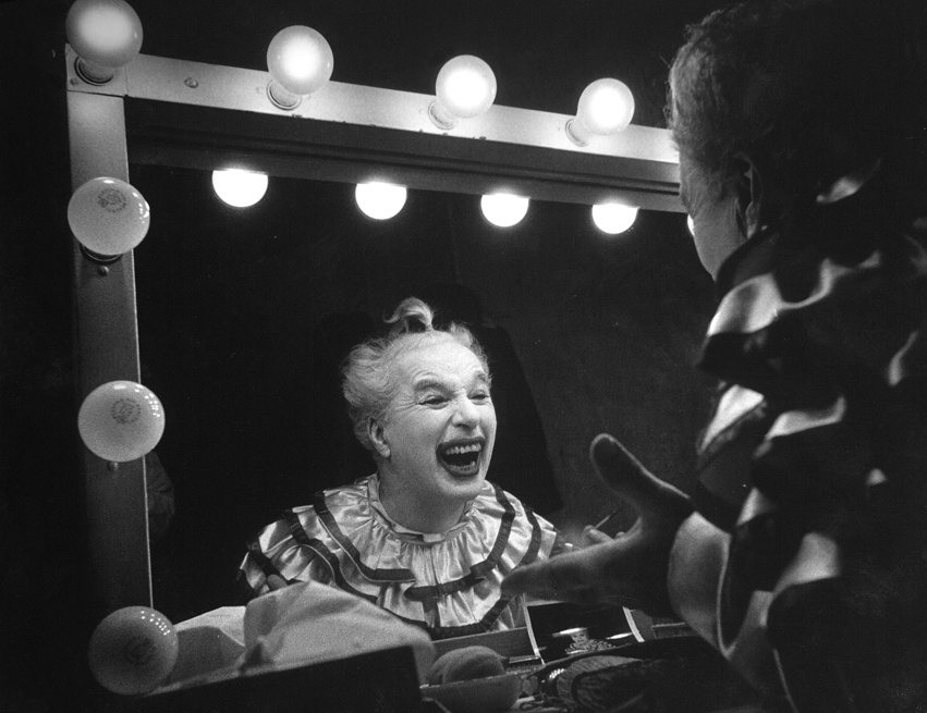 Charlie Chaplin színész az öltözőtükör előtt, amint bohócként széles vigyort vág a Limelight című film forgatásán, 1952