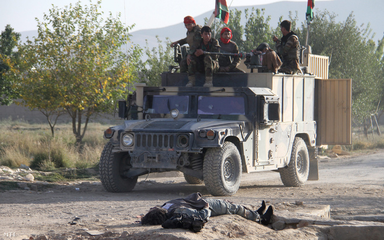 Tálib támadó holtteste mellett halad egy afgán katonákat szállító gépkocsi Gazniban 2015. szeptember 14-én miután tálib lázadók megrohamoztak egy börtönt és rabok százait szabadították ki több rendőrt pedig megöltek.