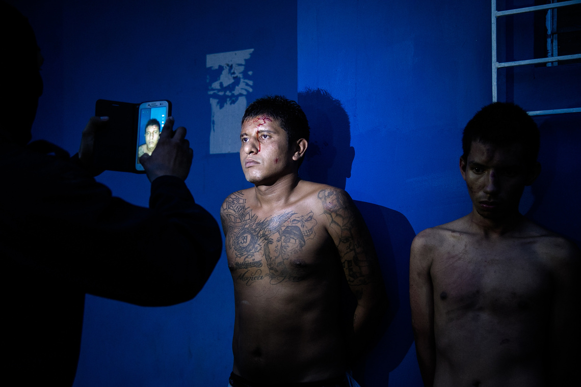 Rendőr készít fényképet egy elfogott Barrio 18 tagról San Salvador egyik rendőrörsén