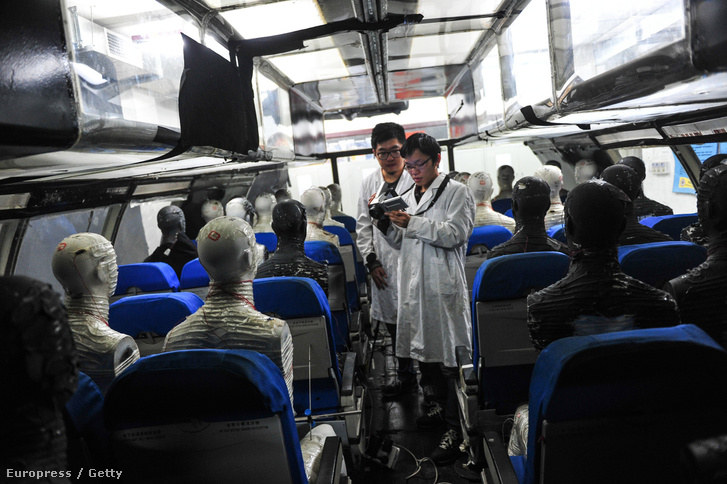 Kínai mérnökök próbautasokkal ellenőrzik a gép utasterének makettjét egy terhelési próbán