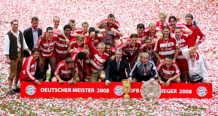 A német labdarúgó-bajnokság győzelmi trófeáját a pajzsot tartó Oliver KAHN-nal a bajnokságban győztes FC Bayern München labdarúgó-csapat visszavonuló kapusával (j-3) és leköszönő edzőjükkel Ottmar Hitzfeld-del (j-4) együtt ünnepelnek a csapattagok a Bundesligában a Hertha BSC Berlin ellen vívott búcsúmérkőzésük után Münchenben 2008. május 17-én.