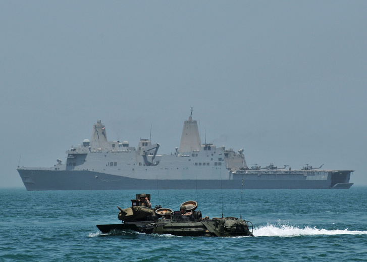 Egy kétéltű jármű szeli a habokat az Arab-tengeren, háttérben a USS New York partraszálló hajó.