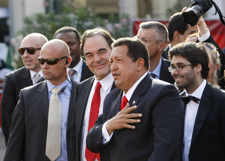 Hugo Chávez és Oliver Stone a testőrök társaságában