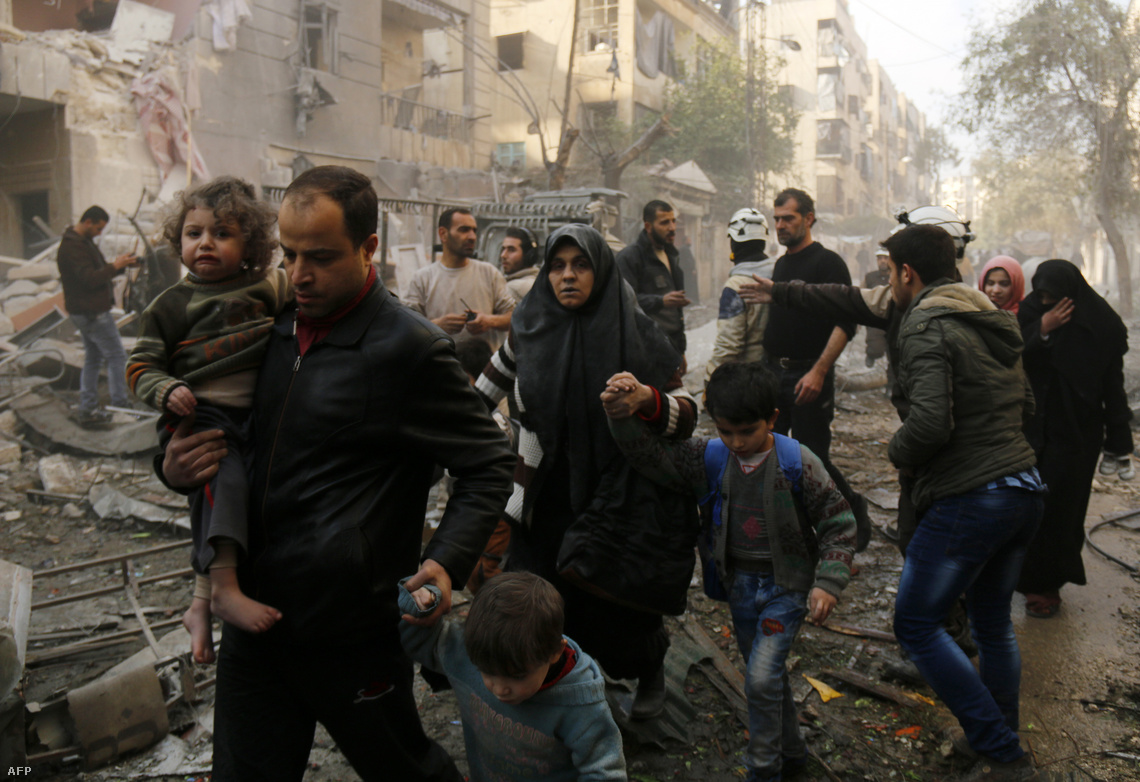 Egy aleppói család a lebombázott otthonuk romjai előtt