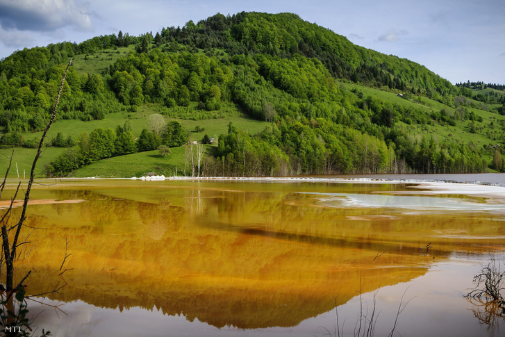 Egy hegy tükröződik a sárgás, vöröses vízben az egykori erdélyi Szászavinc (Geamana) település helyén kialakított zagytározónál 2014. május 11-én. Az 1980-as évek elején kialakított tározóba, a közeli Verespatak rézbányájából folyik a nehézfémekkel szennyezett savas víz.