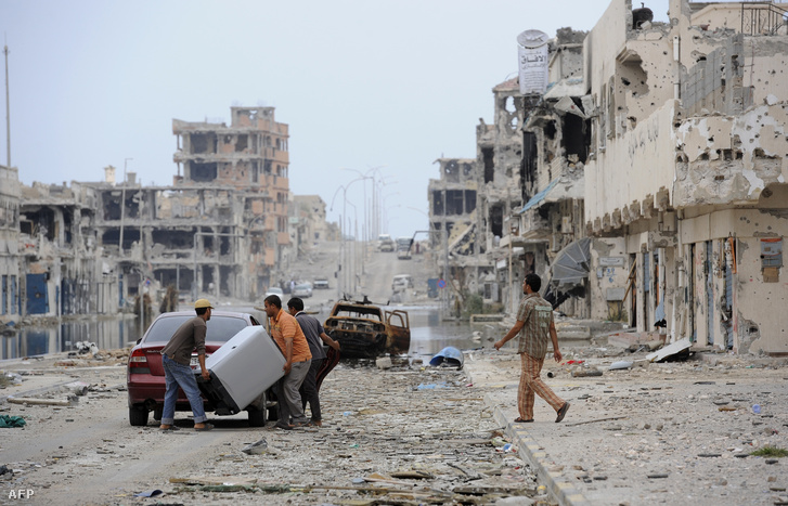 Egy bombatámadás utáni romok között a líbiai lakosok Szirtében.