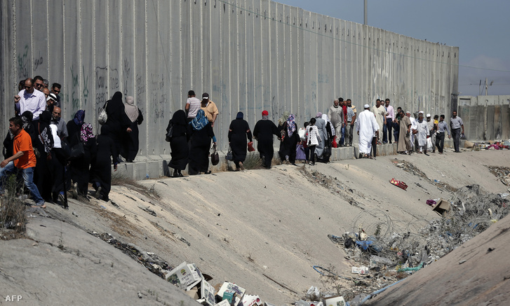 Palesztinok gyalogolnak a Ramallah és Jeruzsálem között korábban felhúzott betonfal tövében.