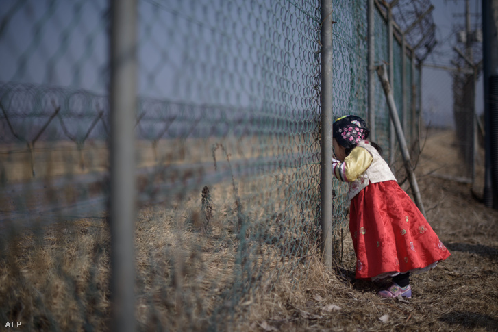 Egy fiatal lány a két Koreát elválasztó demilitarizált zónánál húzódó kerítésnél.