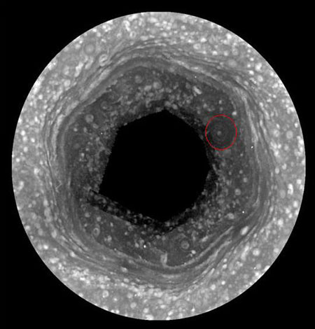 A hatszögletű, globális légáramlat a Szaturnusz északi pólusvidékén, a Cassini űrszonda egyik, 2009-es felvételén. A piros körrel jelzett sötét folt pozíciója éves skálán változik.