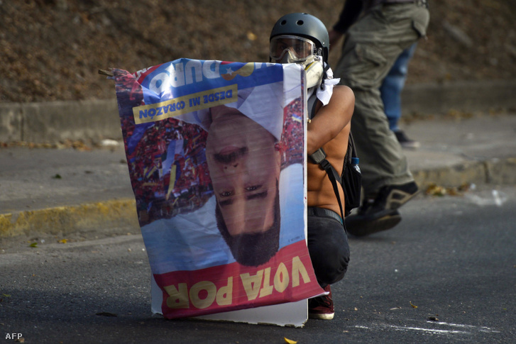 Kormányellenes tüntető Nicolas Maduro választási plakátjával