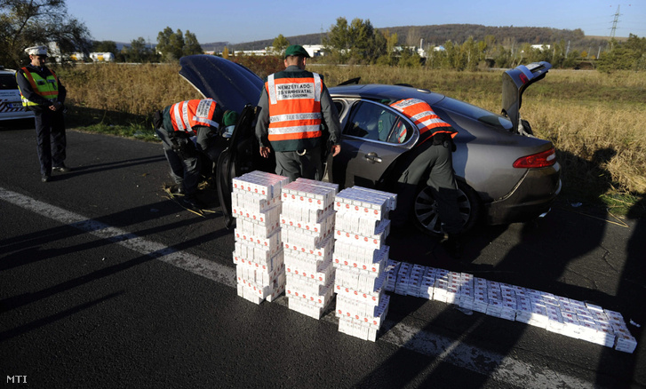 A (NAV) munkatársai egy előzőleg az árokba borult cseh rendszámú autóban talált csempészett dohányárut pakolják ki az M1-es autópályán 2015-ben