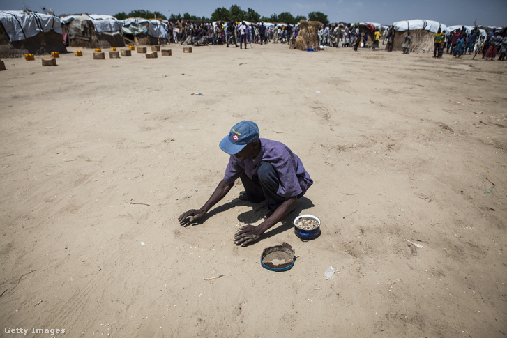 Ételosztás után széthullott babszemeket gyűjt egy férfi Mongunóban, 2016. szeptemberében.
