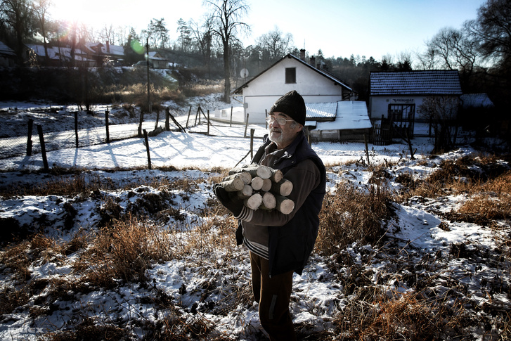 Fát cipel egy férfi a nógrád megyei Karancslapujtőn, az év leghidegebb napján