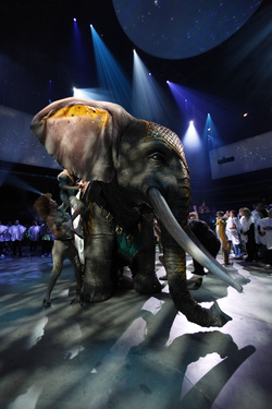A Cirque du Soleil műelefátja, háttérben a fehér poncsósok