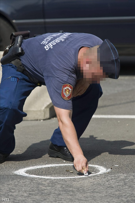 Egy helyszínelő rendőr töltényhüvelyeket rajzol körbe, amint nyomokat rögzít (Fotó: Szigetváry Zsolt)