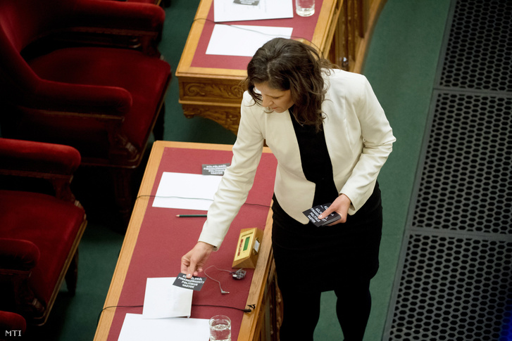 Szél Bernadett az LMP frakcióvezetője "külföldről finanszírozott politikus vagyok" feliratú cédulákat helyez el a kormány tagjainak asztalára az Országgyűlés plenáris ülésén