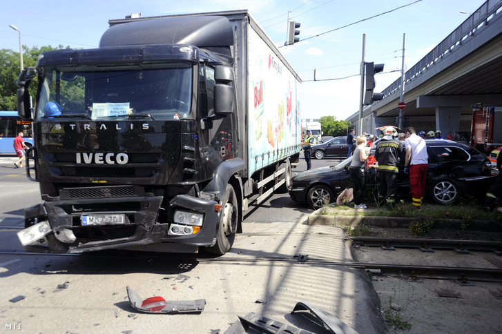 Mentők és tűzoltók látják el a sérülteket egy összetört személyautó mellett a budapesti Határ úton a Gyáli úti felüljáró alatt 2017. május 29-én miután a jármű összeütközött egy teherautóval.