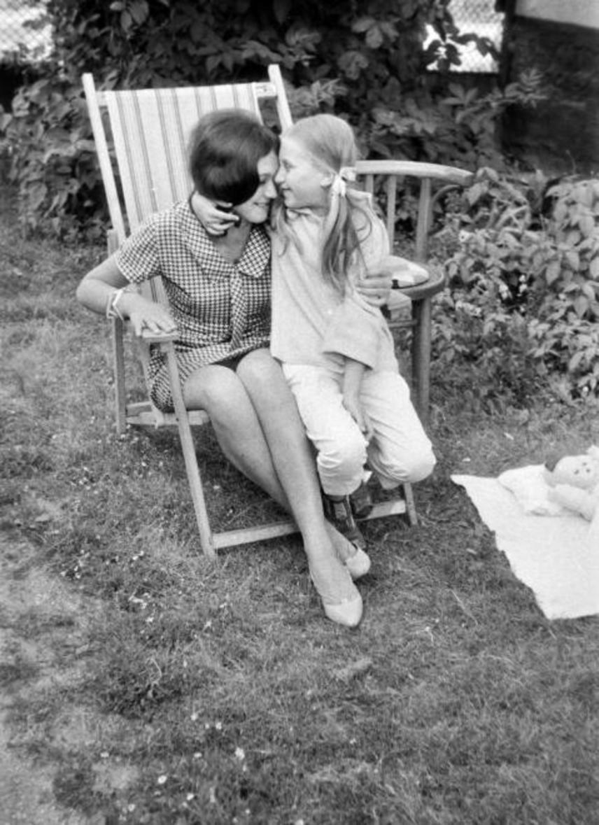 
                        	Idilli felvétel: amíg anya és lánya összebújnak, a játék baba a fűbe terített pokrócon pihen.
                        	(1964)