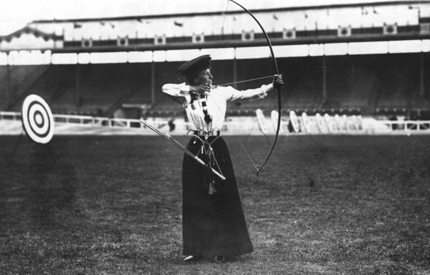 	1908-ban a londoni játékok során Miss Queenie Newall ebben a különös, nagyon tradicionális és mai szemmel aligha sportos összeállításban nyerte meg a női íjászat aranyérmét.