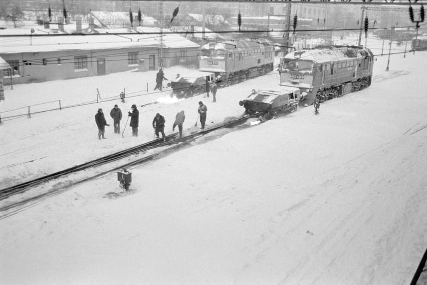 
                        	Lángszórós M62-es, Szergej becenevű mozdonyok melegítik a váltókat a Déli pályaudvaron 1987. január 12-én. A napok óta tartó rendkívüli havazás miatt nagy erőkkel dolgoztak a vágányok megtisztításán.