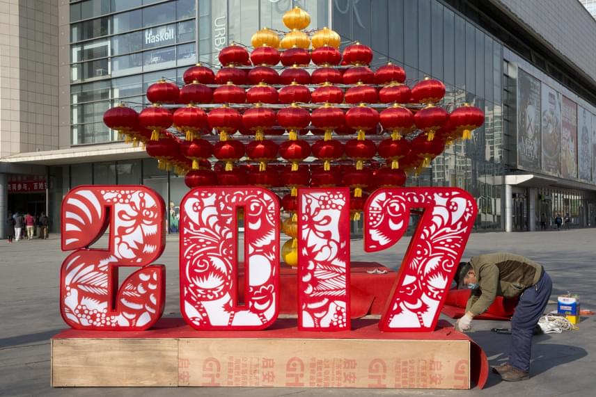 	Egy munkás az utolsó simításokat végzi egy újévi dekoráción egy pekingi bevásárlóközpont előtt 2017. január 23-án. A lampionok és a piros szín hagyományos tartozékai az ünnepnek, a bőséget, a szerencsét, a gazdagságot szimbolizálják.