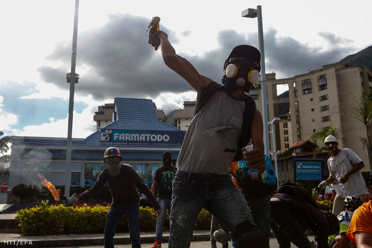 Tüntetők Molotov-koktélokat dobnak a rohamrendőrök irányába a Nicolas Maduro venezuelai elnök kormányzata elleni tiltakozáson Caracasban 2017. június 14-én.