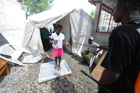 Egy haiti lány lép fertőtlenítő vízbe, mielőtt beengedik a kórházba