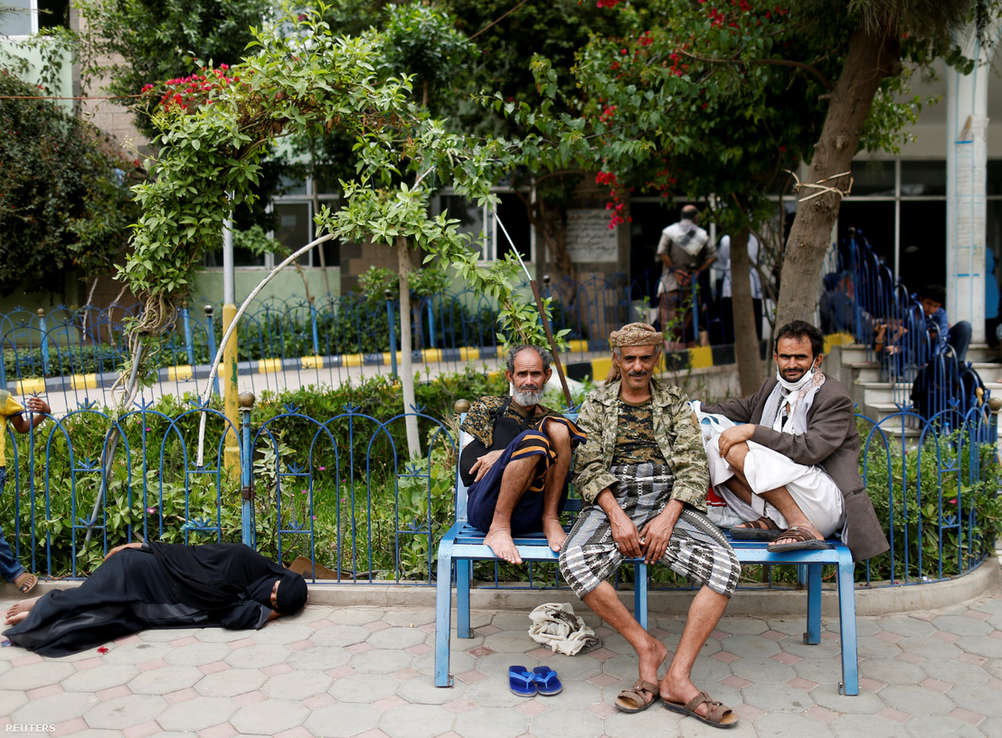Férfiak ülnek a padon, egy nő pedig a földön fekszik egy kolerás beteg számára fenntartott intézmény udvarán, Szanaában.