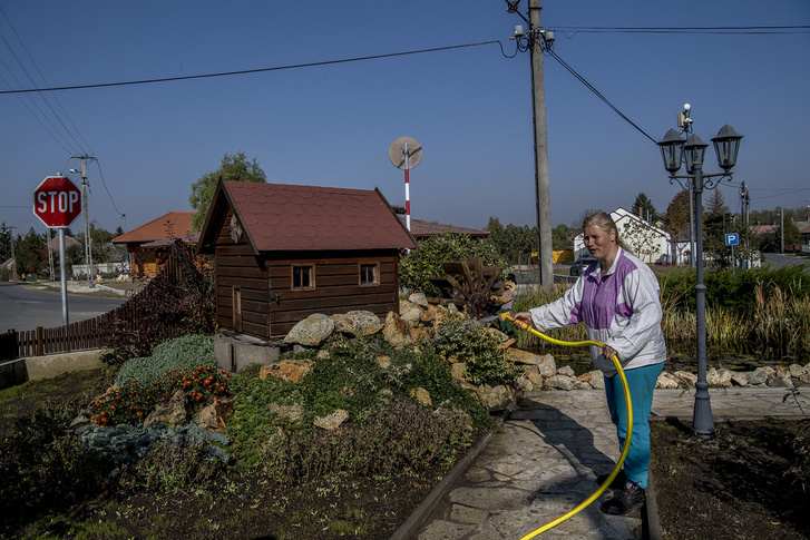 Közmunkás locsolja a frissen kialakított virágágyásokat a faluközpontban