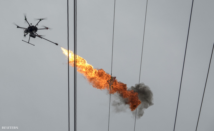 A hainani elektromos művek egyik dolgozója távirányítású hexakopterrel égeti le a nagyfeszültségű távvezetékre rátekeredett sárkányt.