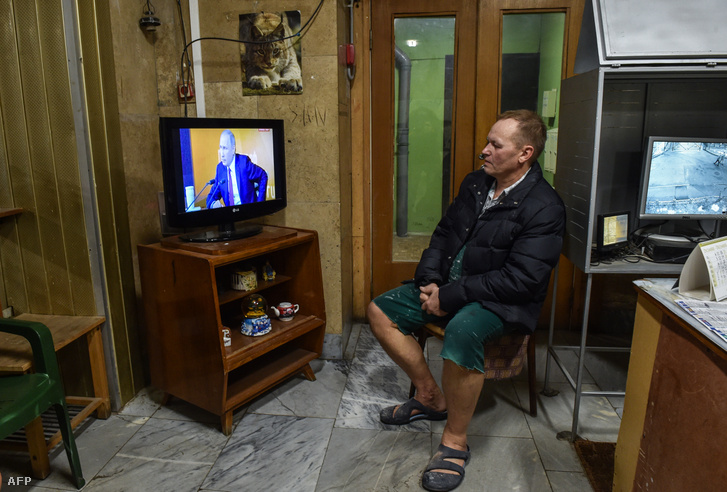 Egy férfi nézi az orosz elnök televíziós sajtótájékoztató műsorát egy moszkvai ház előcsarnokában 2017. december 14-én