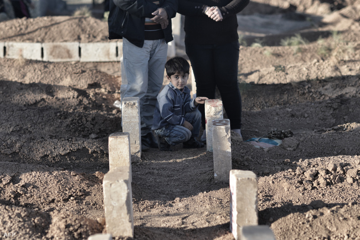 Kurd kisgyerek az YPG és az YPJ halottjainak sírjai között, Kobaniban
