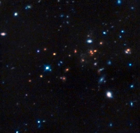 A CL J1449+0856 katalógusjelű galaxishalmaznak a Hubble Űrteleszkóp NICMOS (Near Infrared Camera and Multi-Object Spectrometer) műszerével rögzített képe, melyre a területről a VLT és a Subaru teleszkópokkal készített felvételeket montírozták. A képen a legtöbb objektum távoli, halvány galaxis. A CL J1449+0856 tagjai a kép középső területén látható vörös foltok. Fotó: NASA, ESA, R. Gobat (Laboratoire AIM-Paris-Saclay, CEA/DSM-CNRS-Université Paris Diderot)