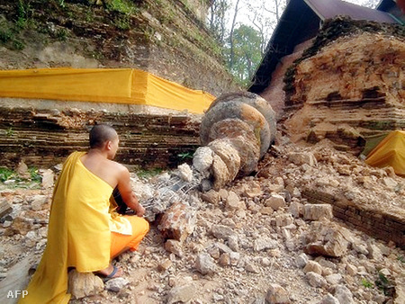 Buddhista szerzetes nézi egy pagoda földrengés miatt eldőlt oszlopát