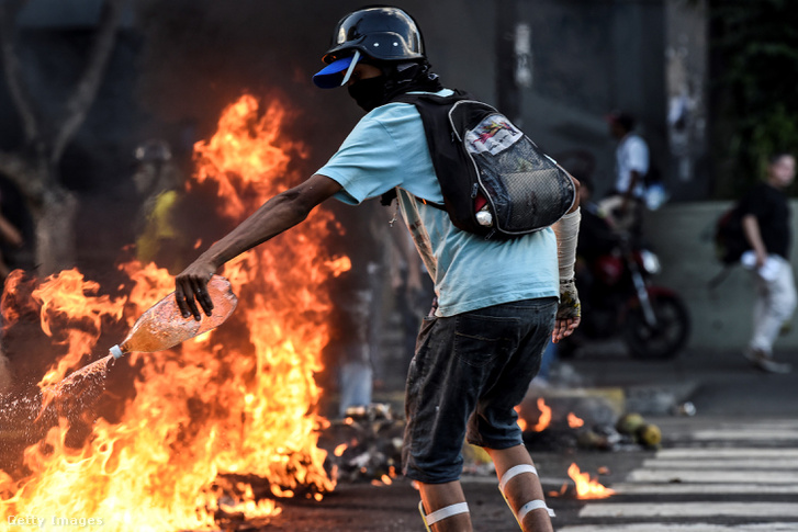 Maszkos tüntető benzint ön a lángokra Nicolas Maduro elnök kormánya elleni tiltakozáson. Caracas, Venezuela, 2017.05.20.