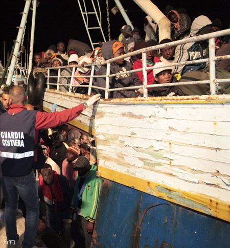 Az olasz parti őrség tagjai segítenek a Líbiából érkezett, illegális bevándorlókkal teli hajó utasainak a partraszállásban az olaszországi Lampedusa kikötőjében