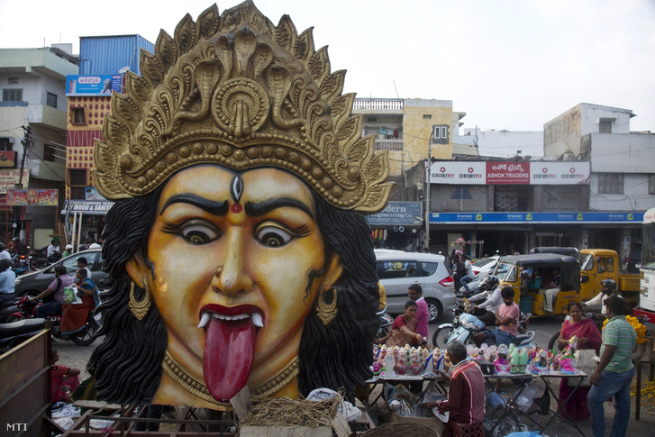Kegytárgyakat vásárolnak indiaiak a díváli hindu fényünnep kezdetén Haidarábádban 2018. november 6-án, az előtérben Kálit, a halál és újjászületés istennőjét ábrázoló hatalmas fejszobor.