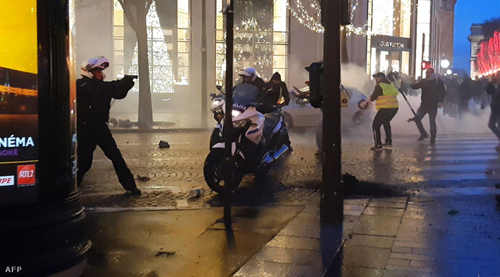 Egy motoros rendőr fegyvert fog a tüntetőkre Párizsban, 2018. december 22-én