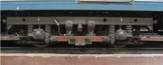 A metrókocsik áramszedőjét, a kép közepén látható papucsot, a jármű forgóvázától a vörös színű áramszedő gerenda választja el