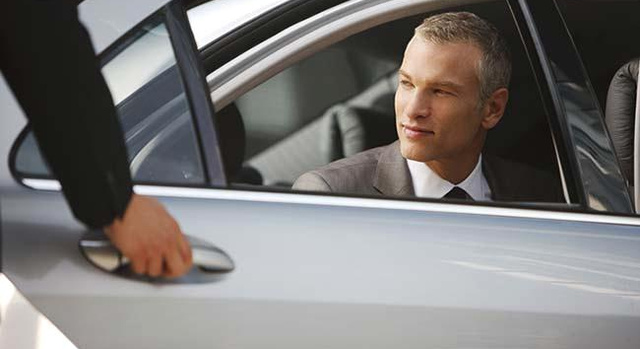 Chauffeur opening car door for businessman pe0074462
