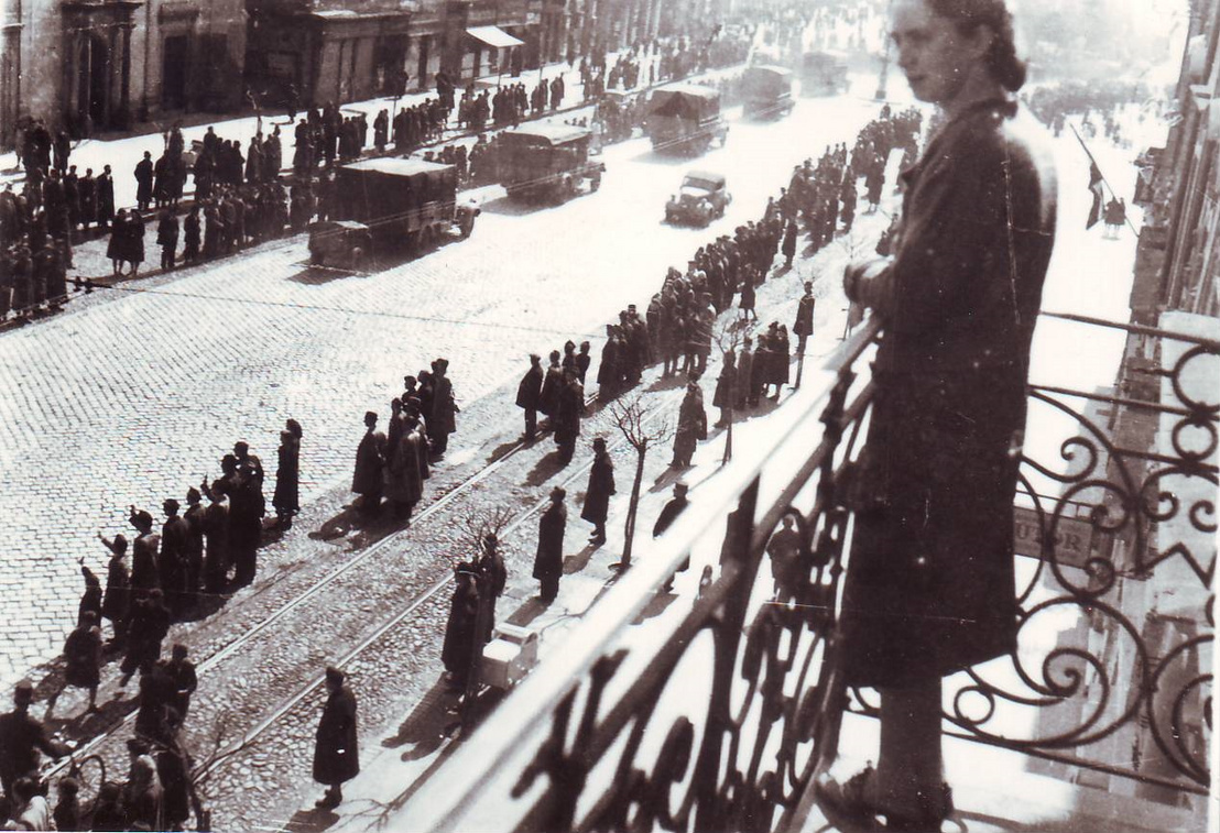 Kelemen tanár úr felesége, Franck Ilona 1944 márciusában, a német megszállás után a kassai Fő utca 90. erkélyén. Az utcán masírozó katonák és bámészkodó tömeg.
