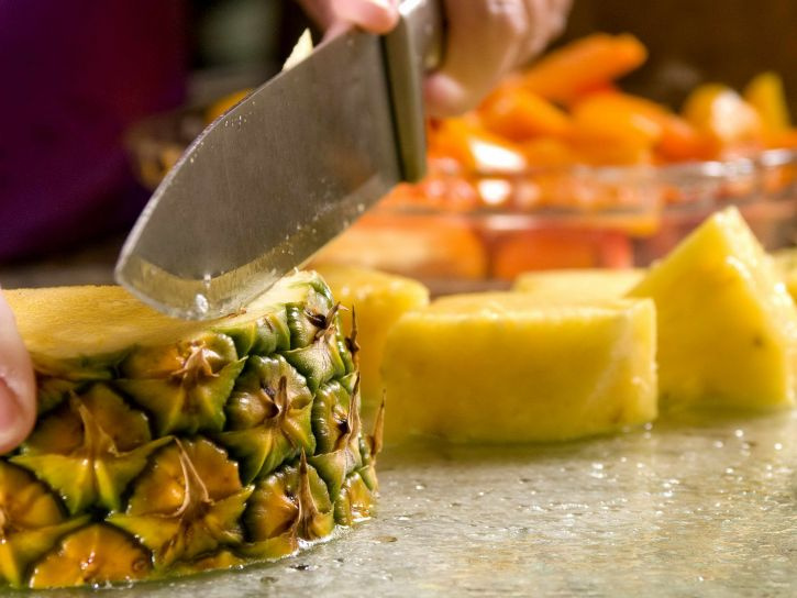 slicing-a-freshly-cleaned-whole-pineapple-atop-a-clean-glass-cut