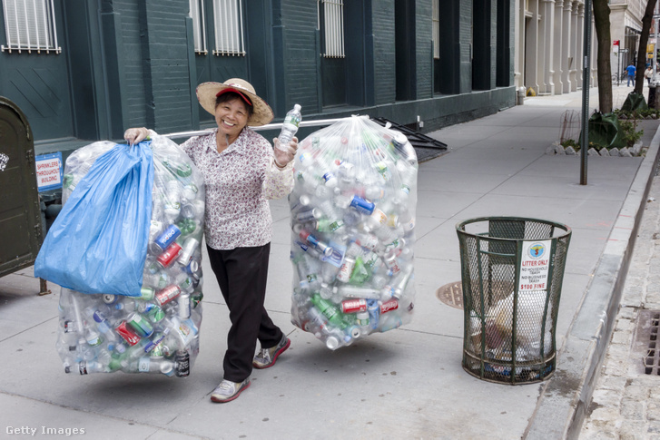 Asian woman walking with bags of recyclable plastic and metal bottles.