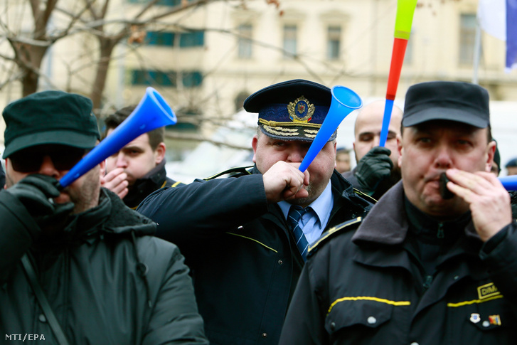 Tüntető fegyőrök tülköt fújnak a bukaresti belügyminisztérium előtt 2019. február 7-én. A tüntetésen rendőrök, fegyőrök és nyugállományú katonák követeltek jobb munkafeltételeket, valamint magasabb fizetést és nyugdíjat.