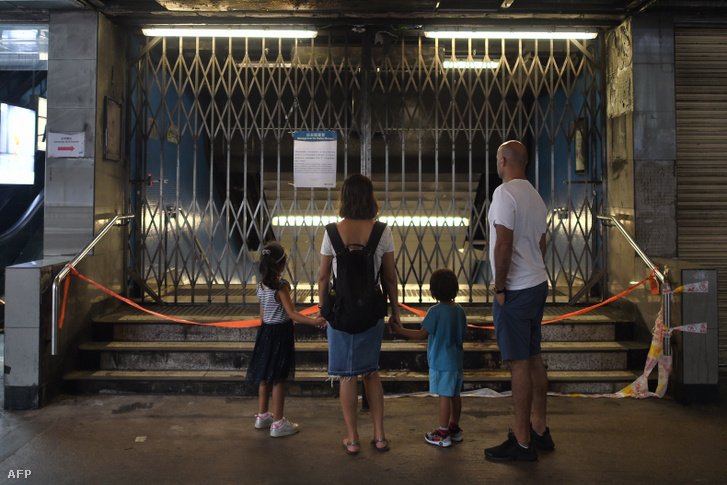 Egy család a lezárt metróállomás előtt Hongkongban vasárnap