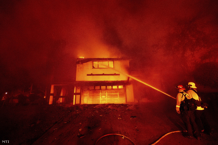 Erdőtűz miatt kigyulladt lakóépület lángjaival küzd egy tűzoltó a kaliforniai San Bernadino városban 2019. október 31-én.