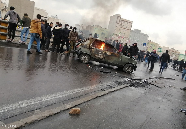 Tüntetők egy lángoló autónál Teheránban 2019. november 16-án, miután a kormány az üzemanyagárak jelentős emelését és a jegyrendszeralapú tankolás bevezetését helyezte kilátásba.