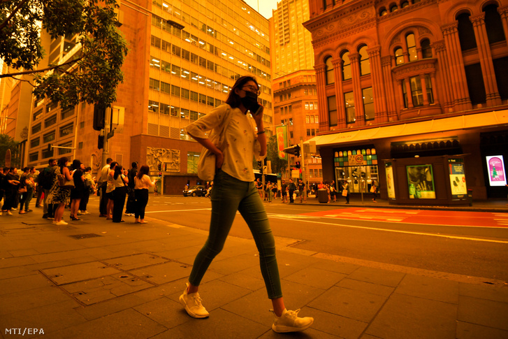 Védőmaszkot viselő gyalogos a Sydney-t beborító bozóttűz füstjében 2019. december 6-án