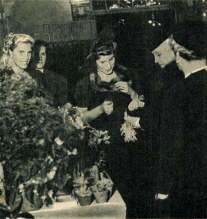 Horthy Miklósné (jobb oldalon, a háttal álló hölgy mellett) virágcsokrot vásárol a karácsonyi jótékonysági vásáron. ( Tolnai Világlapja, 1939. december 13.)
