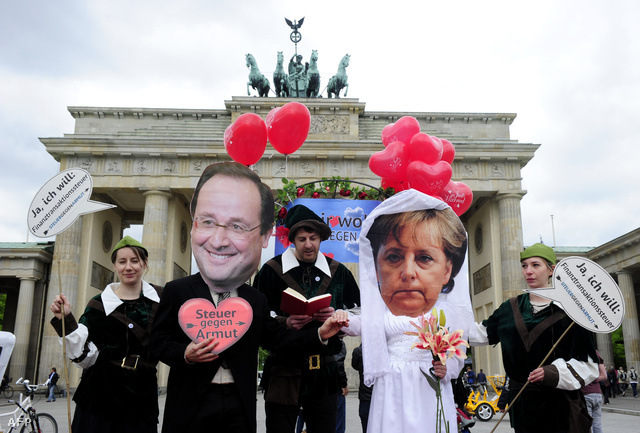 Berlini aktivisták Hollande és Merkel maszkban a Brandenburgi kapunál